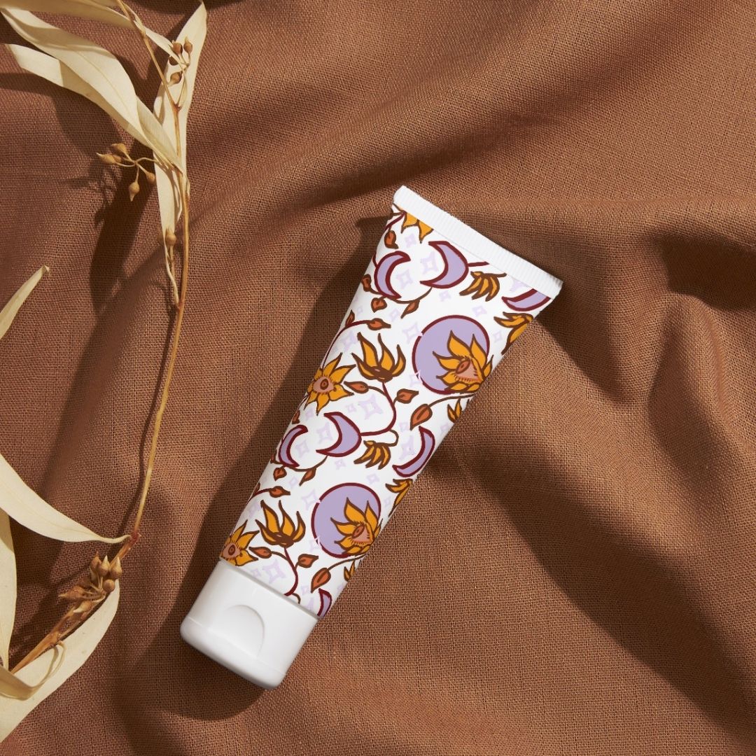 Celestial Bloom pattern in violet on a cosmetic tube against linen